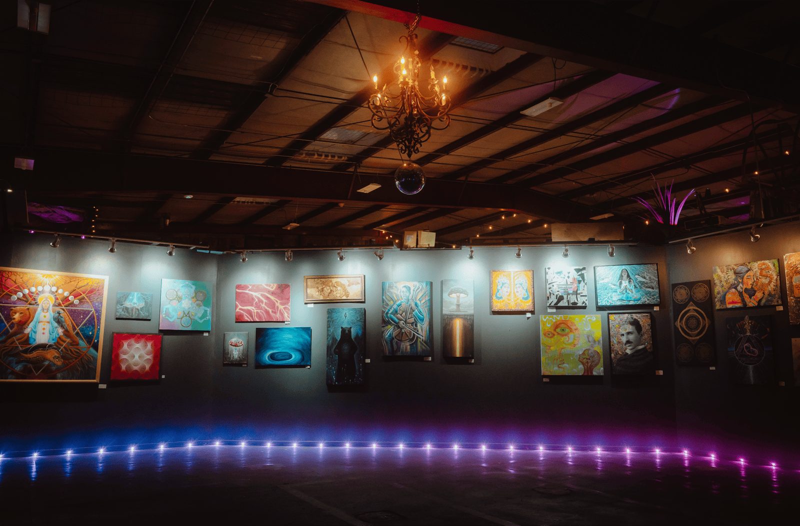A gallery wall at The Haven PDX hung with original paintings and lit from below